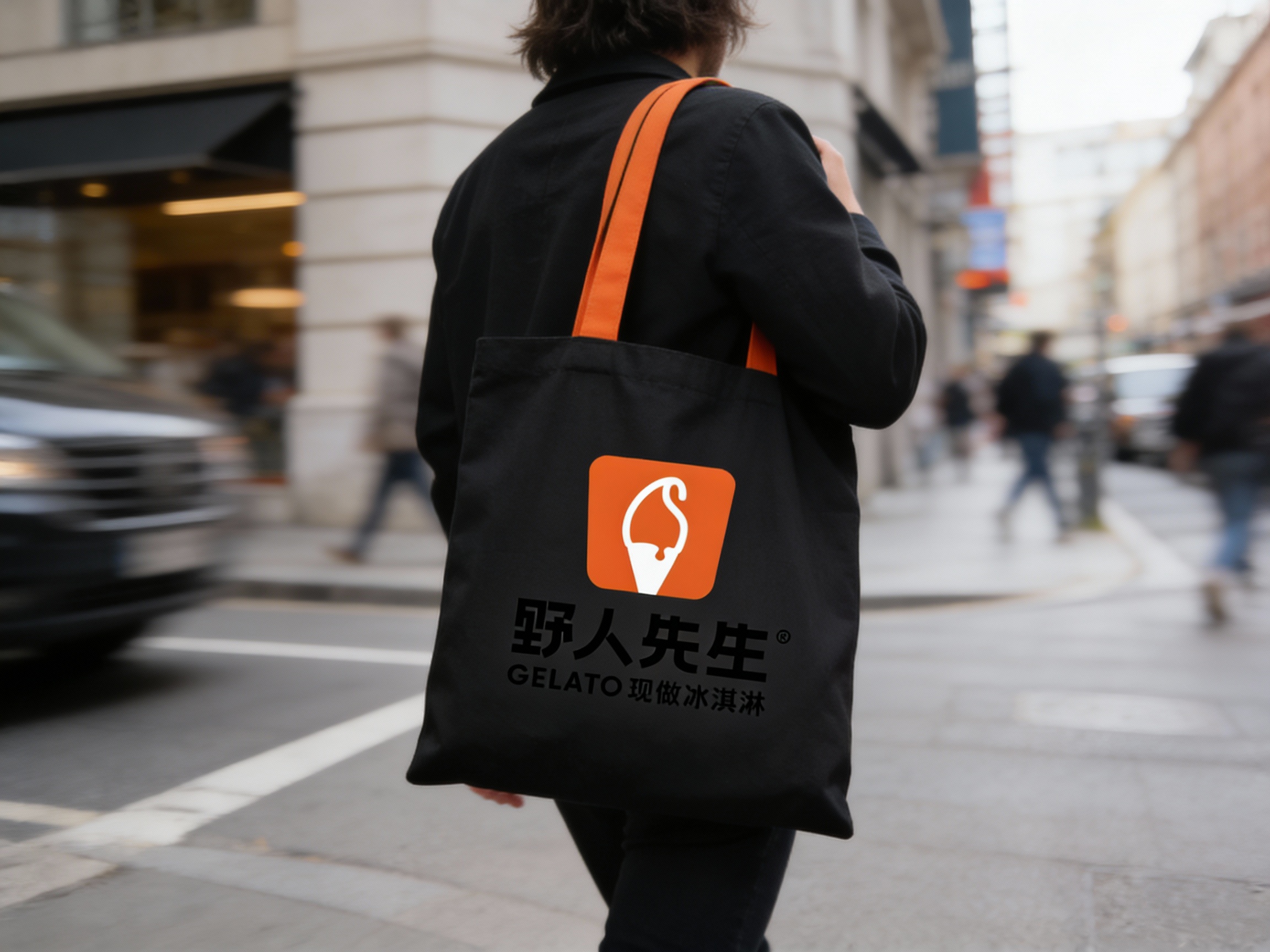 一张潮流街拍风格的背影图。模特背对着镜头行走在都市街头，肩上背着一个极简设计的黑色帆布手提袋。手提袋的肩带运用了鲜明的品牌色（基于参考图主色调），袋身上清晰印着（将参考图中的LOGO）。自然光线，街景虚化，捕捉行进中的动态感，重点展示手提袋作为时尚单品的搭配效果及品牌标识的辨识度。