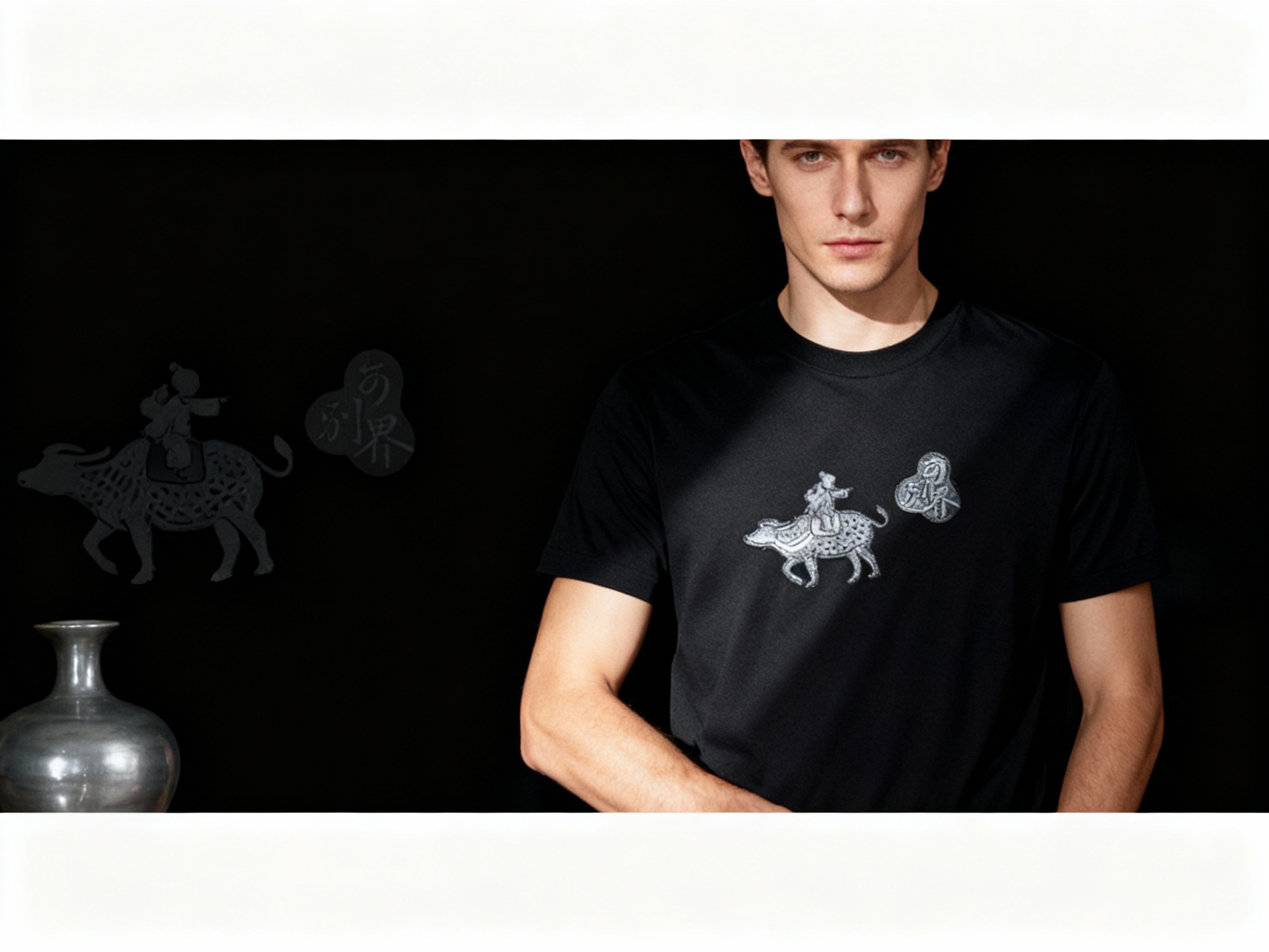 提取参考图的LOGO单独呈现，改为银灰色，25岁欧洲男性模特，穿黑色重磅T恤，银灰色LOGO采用镂空刺绣+内嵌反光条工艺，暗光环境拍摄，局部射灯斜照LOGO，反光条呈现柔和光泽，不刺眼，模特手臂自然弯曲，T恤贴合身形却不紧绷，背景为极简黑色，画面左侧放置一个银灰色陶瓷花瓶，与LOGO材质感相呼应，整体高级冷峻